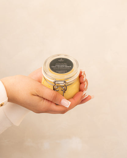 Patchouli Face Moisturiser on a minimal background in the hand of a model, green label for eczema, dermatitis, and dry skin.