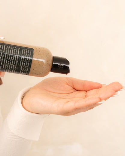 Patchouli Face Wash on a minimal background in the hand of a model, green label for eczema, dermatitis, and dry skin.
