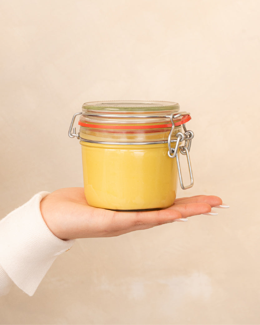 Patchouli Body Butter on a minimal background in the hand of a model, green label for eczema, dermatitis, and dry skin.