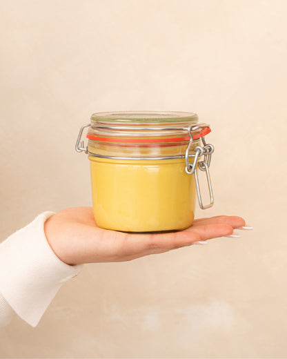 Patchouli Body Butter on a minimal background in the hand of a model, green label for eczema, dermatitis, and dry skin.